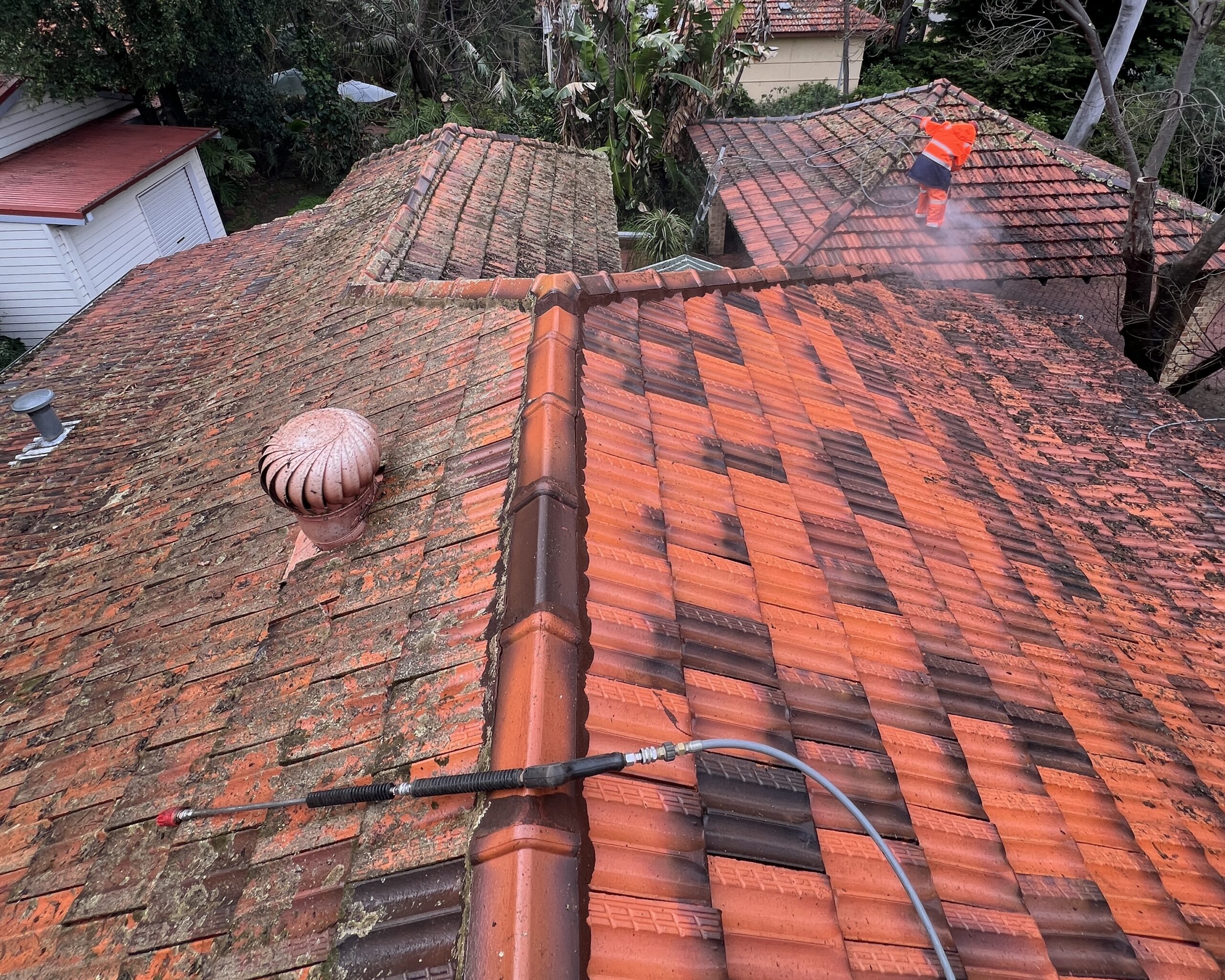 Professional terracotta roof cleaning removing heavy lichen with controlled pressure washing in Perth.